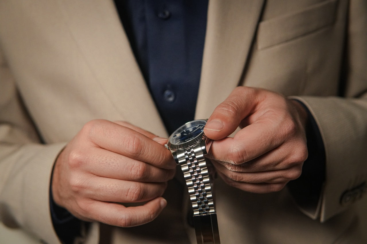 Man adjusting his steel Valenne left-handed watch, highlighting the 5-link jubilee bracelet and fluted bezel.